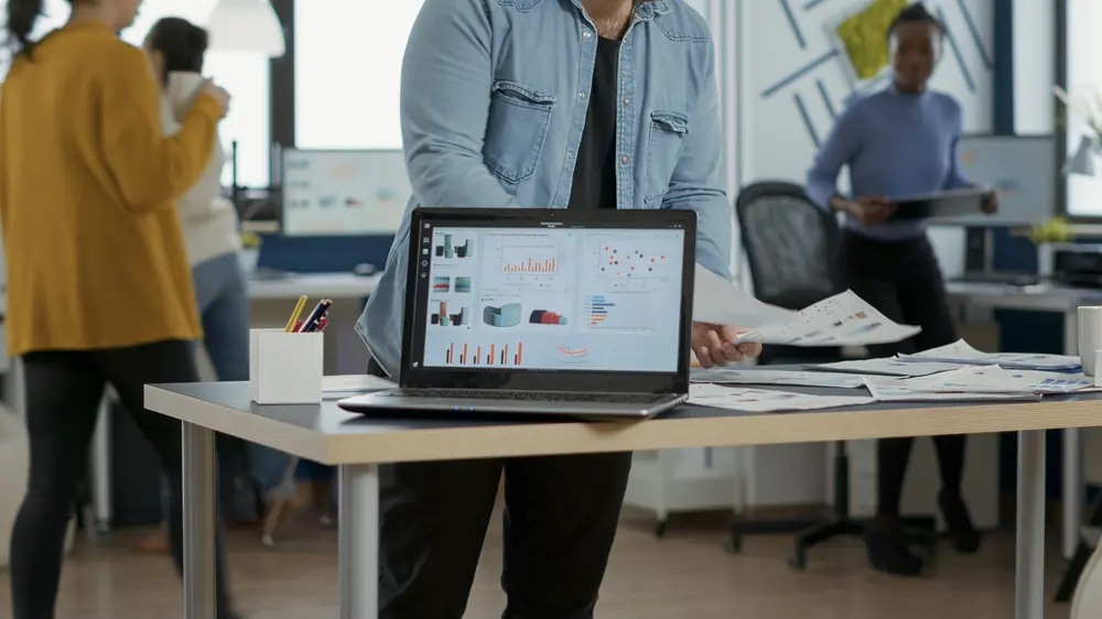 Notebook com gráficos de desempenho em um escritório movimentado