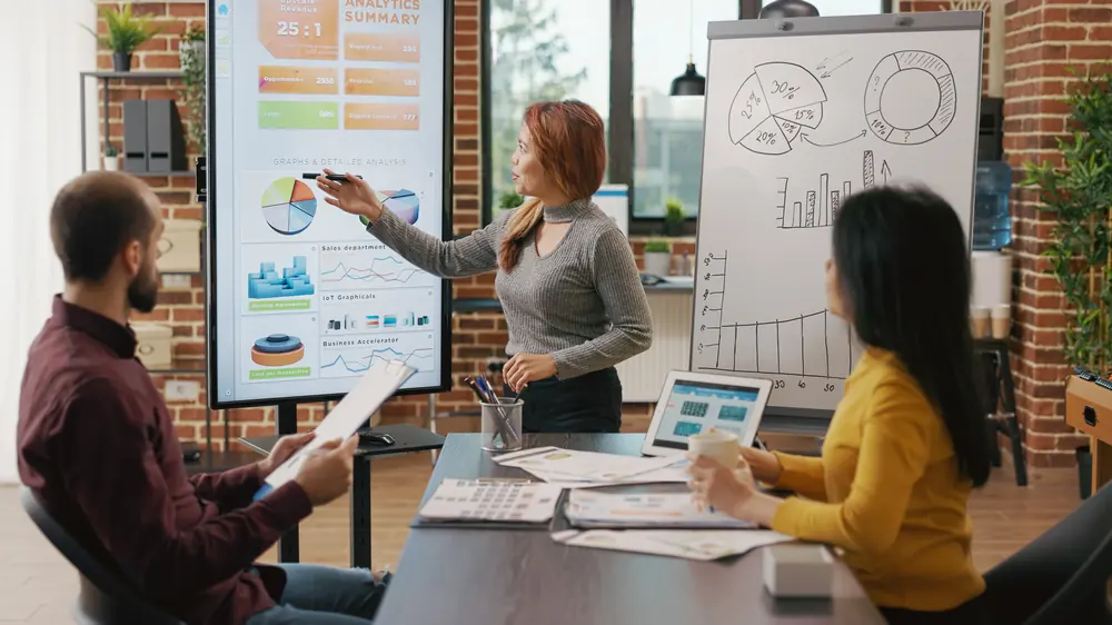 Equipe planejando estratégia de marketing diante de uma tela de indicadores (foto de banco de imagens)