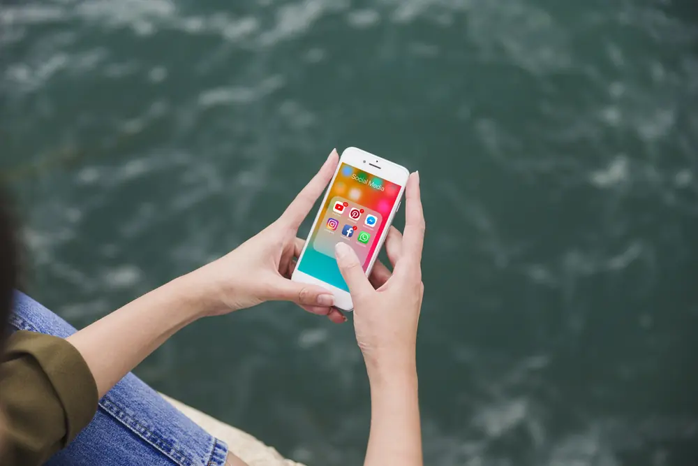 Mãos segurando um celular com notificações de redes sociais