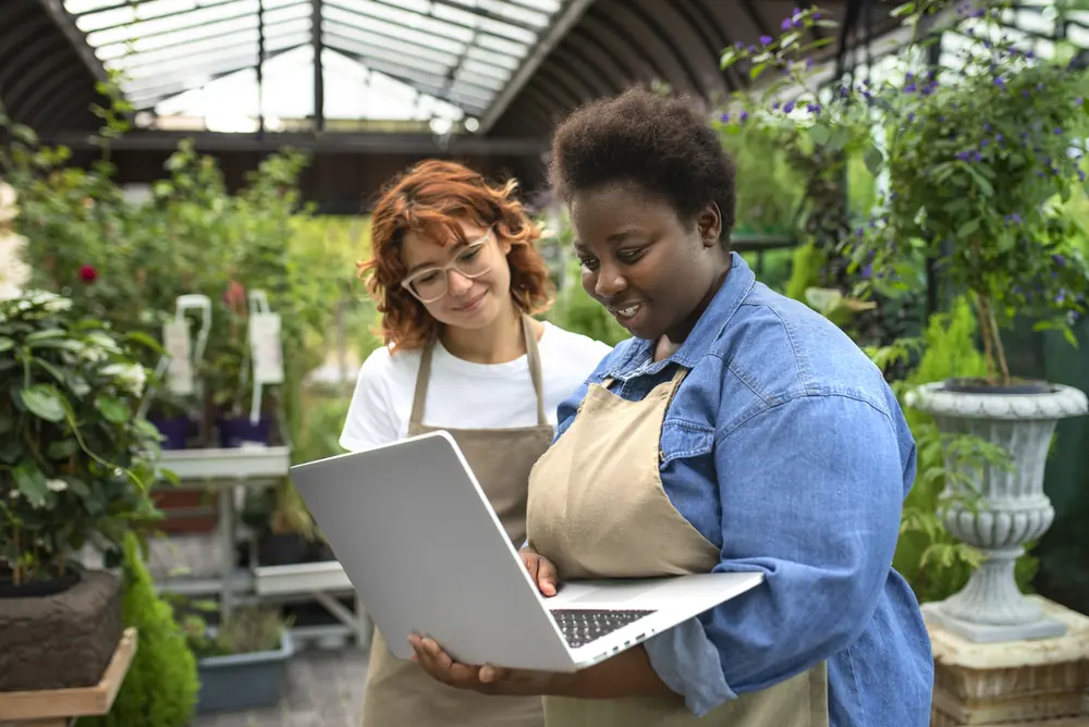 Duas empreendedoras de uma loja de plantas olhando um notebook