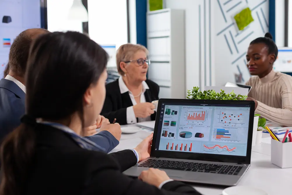 Equipe em reunião analisando gráficos de campanha em um notebook