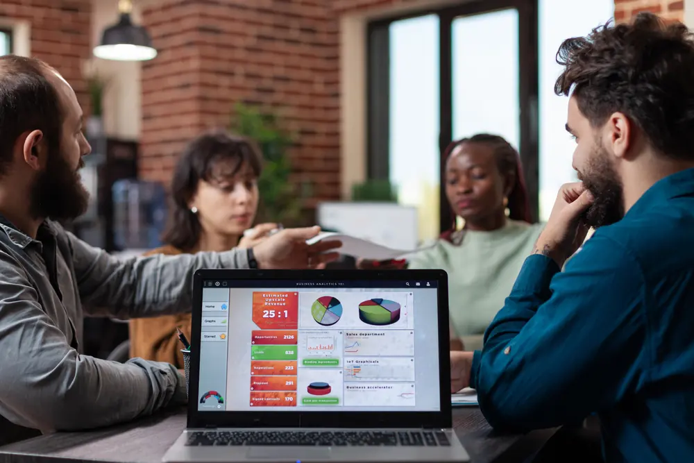 Equipe reunida em torno de um notebook com gráficos de marketing