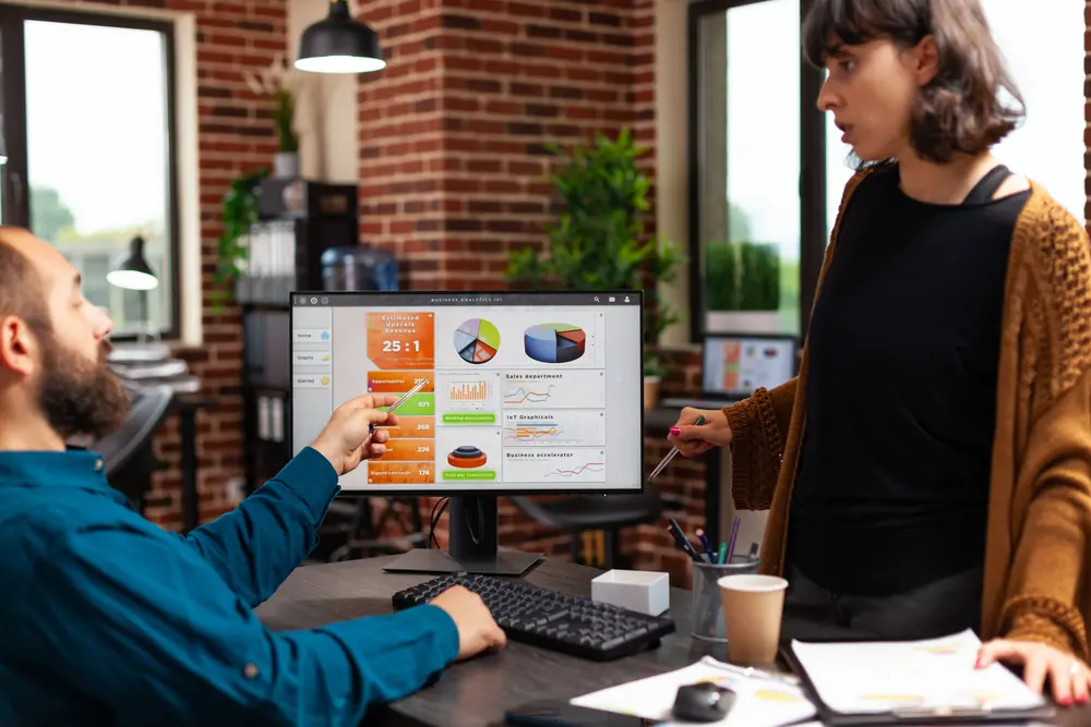 Profissionais de marketing discutindo gráficos de desempenho em um monitor