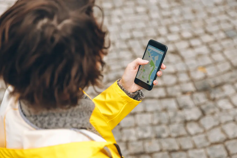Pessoa consultando um mapa no celular em uma rua de pedra