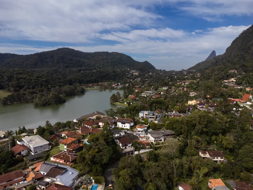 Vista aérea de um bairro de Teresópolis, com lago e montanhas ao fundo
